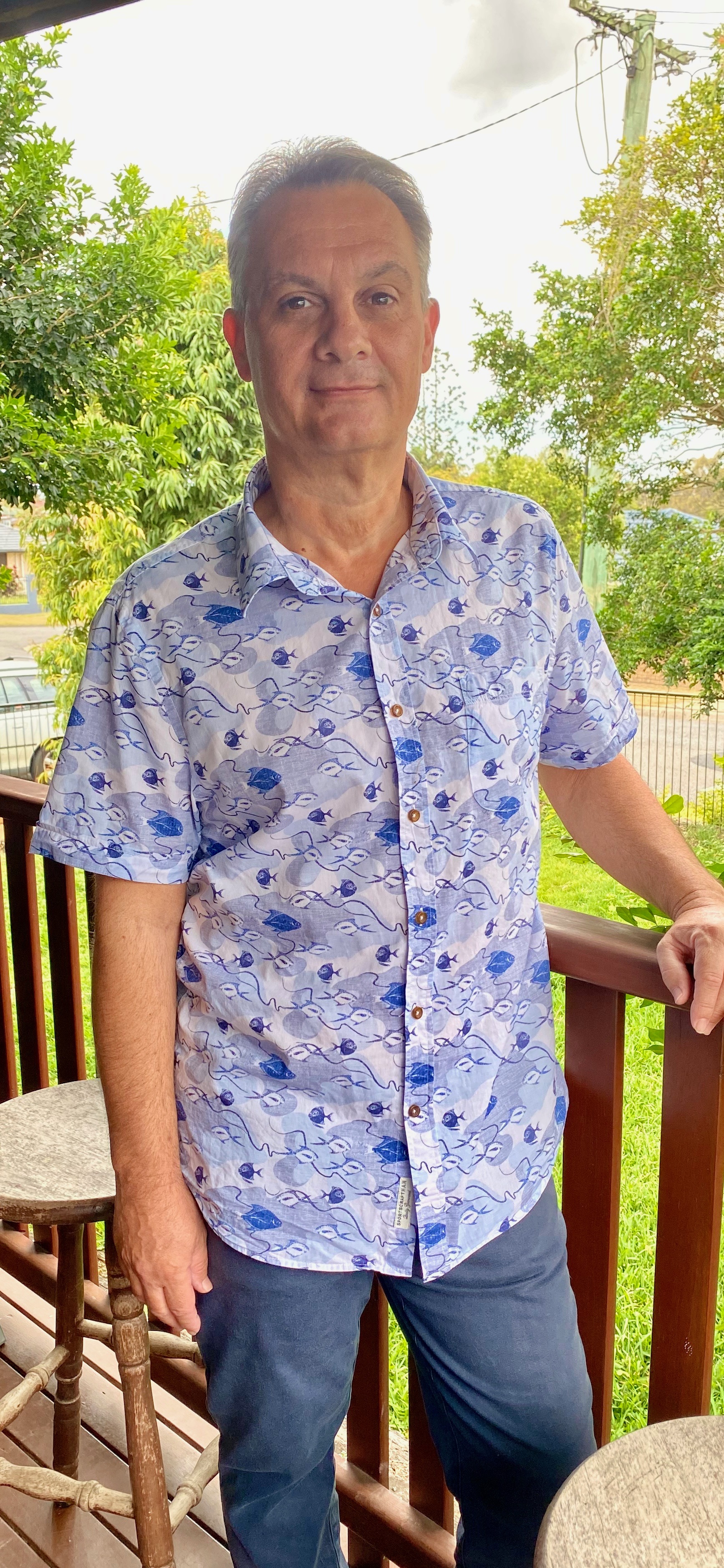 Rob, standing on a sunlit deck surrounded by greenery